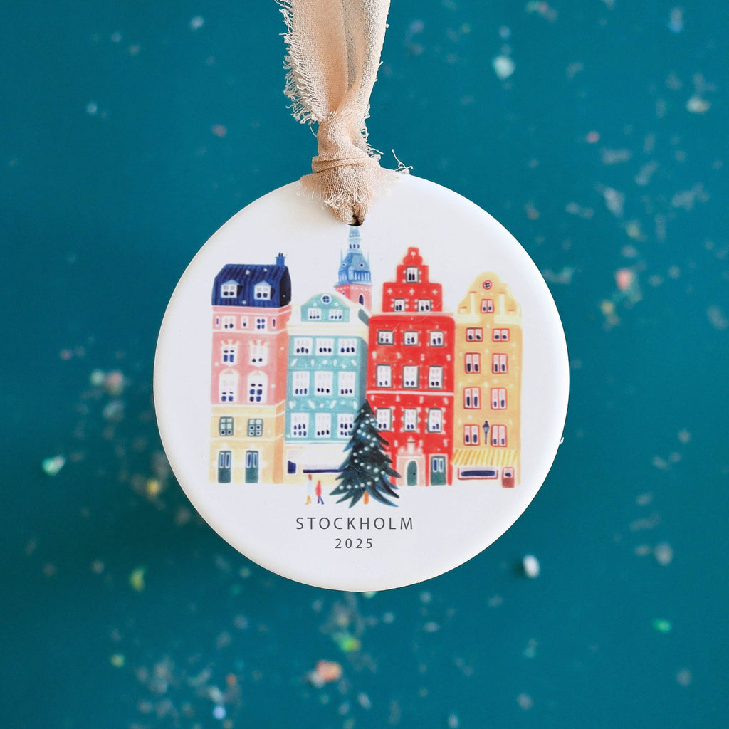 Round Christmas ornament with colorful buildings and 'Stockholm' text on a blue background